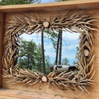 Handcrafted rectangle mule deer antler mirror reflecting forest scenery