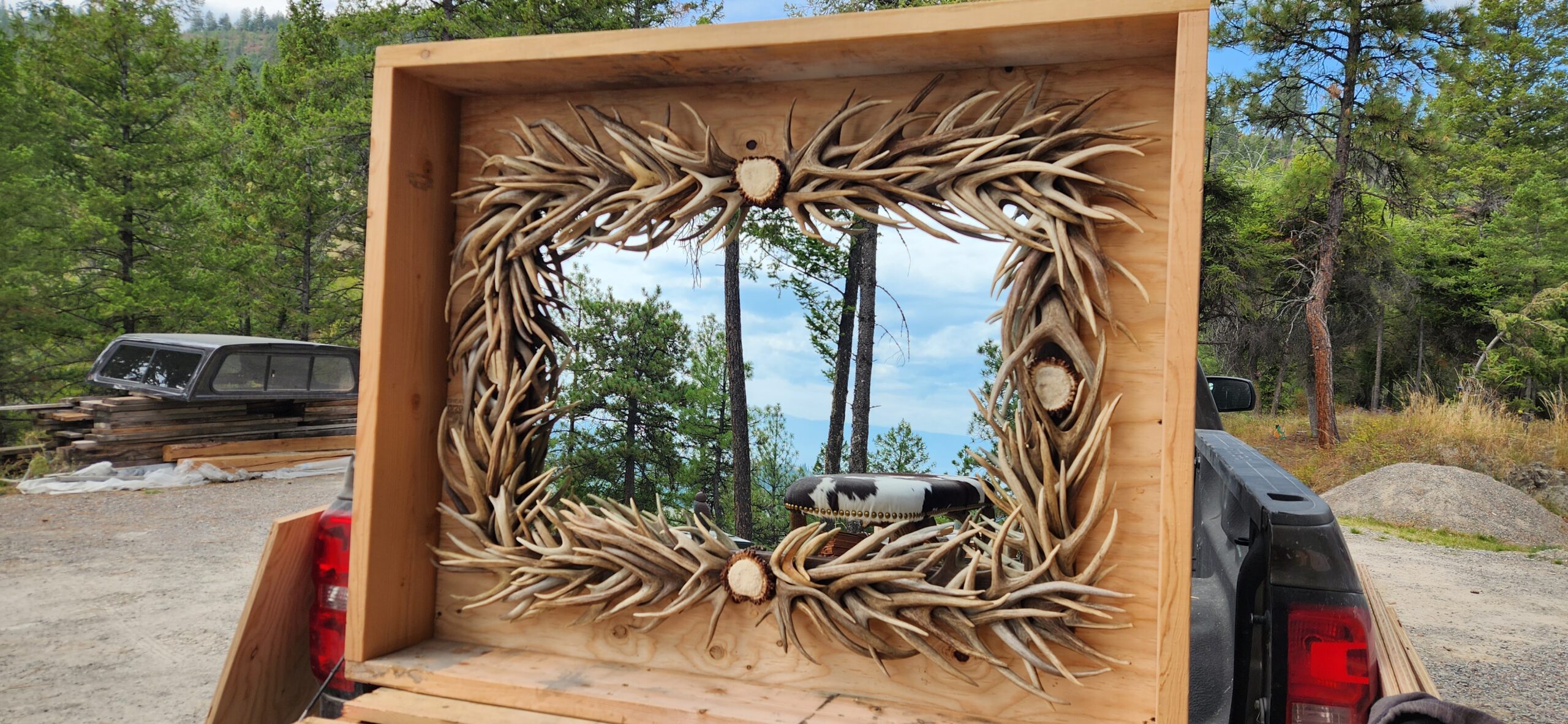 Handcrafted rectangle mule deer antler mirror reflecting forest scenery