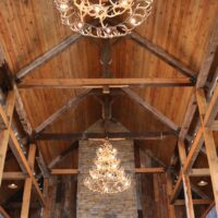 View from below of vaulted barn wood lodge with two large whitetail antler chandeliers