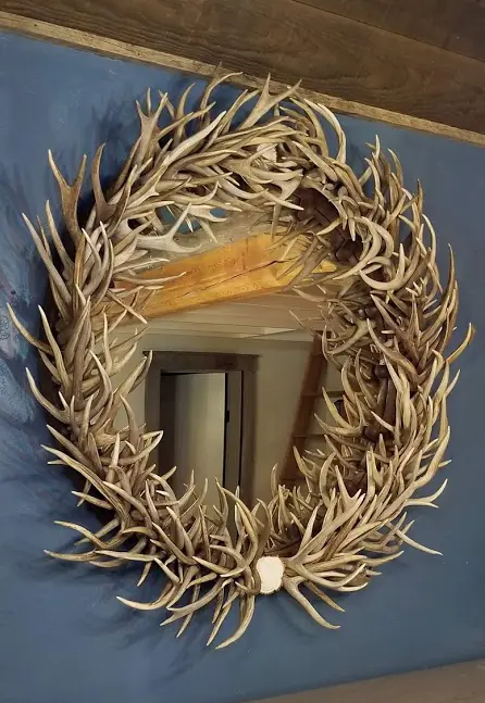 Round wall mirror handcrafted from genuine whitetail antlers with a rustic wooden back
