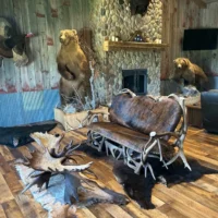 A high-end rustic sofa featuring a unique frame made from genuine shed deer antlers and premium cowhide upholstery, displayed in a lodge-style showroom.