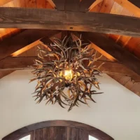 Handcrafted Tumbleweed mule deer antler ball chandelier hanging from a vaulted timber ceiling.