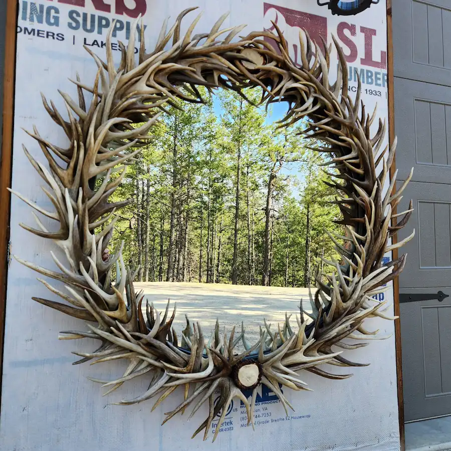 Round wall mirror framed by natural, handcrafted deer antlers.