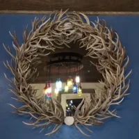 Round wall mirror handcrafted from genuine deer antlers with a rustic finish.