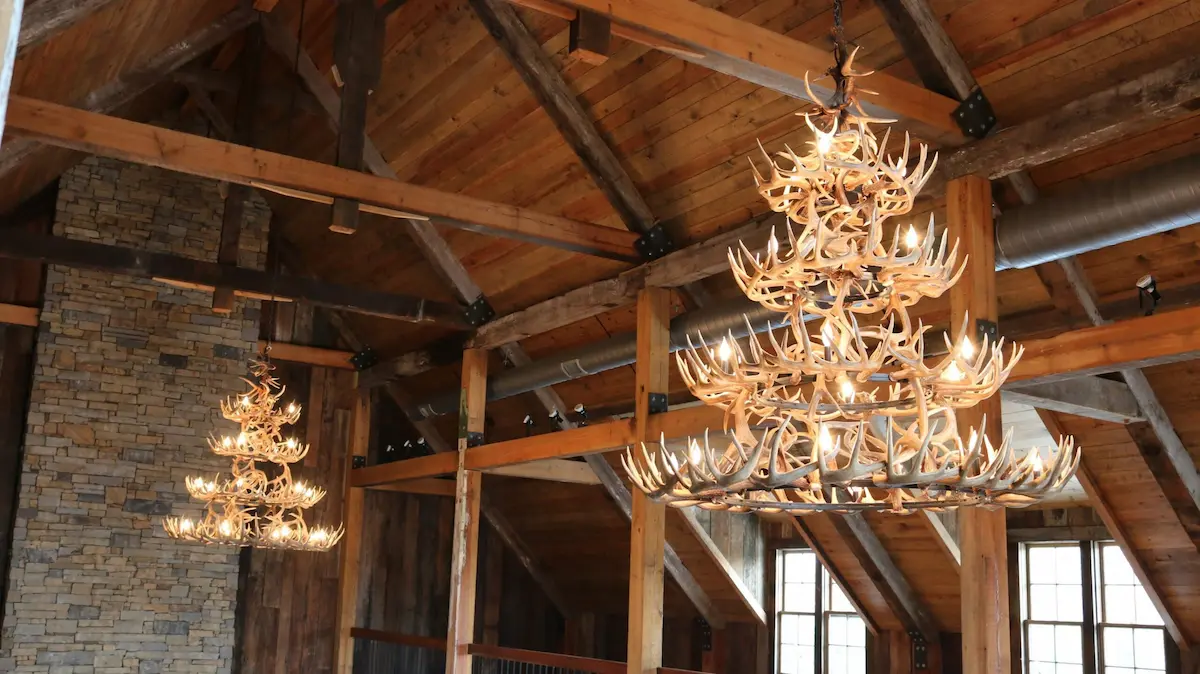 Handcrafted 4-tier trophy whitetail antler chandelier hanging in a rustic timber-frame great room.